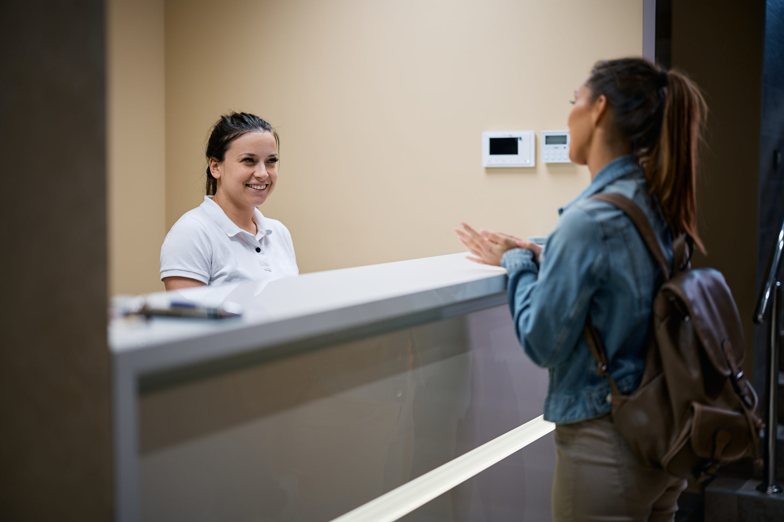 Happy receptions talks to a woman who is checking in at physical therapy center.